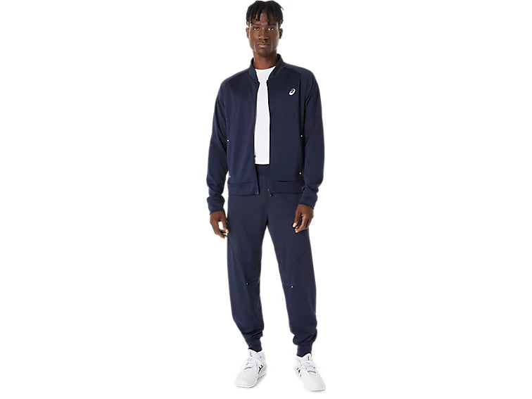 hombre usando chaqueta asics court warm up jacket midnight durante calentamiento en cancha tenis